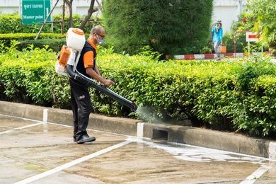 Technician spraying mosquito treatment in a garden area